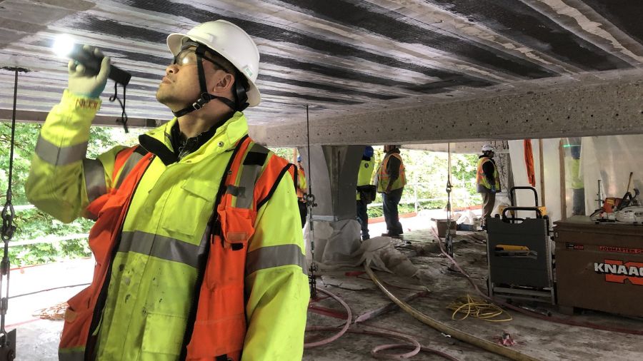 Photo: SDOT Roadway Structures Director Kit Loo inspects newly installed carbon fiber wrapping unde...