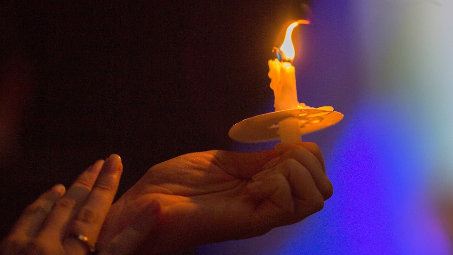 Image: A person holds a candle at a memorial and vigil outside Los Angeles City Hall in November 20...