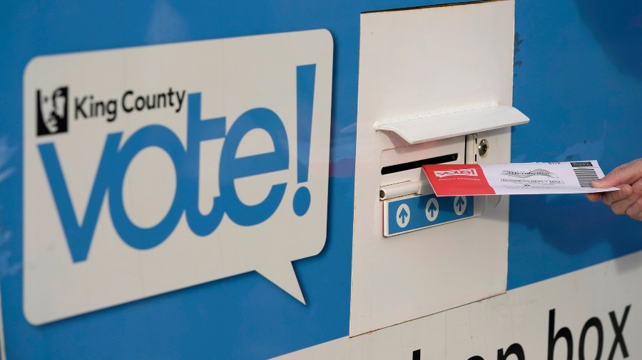 Image: A person puts their ballot in a drop box on Oct. 27, 2020 at a library in Seattle....