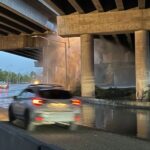 Cars pass as water spewing from a burst pipe underneath Highway 99 in Seattle’s South Park neighborhood. (Photo: Sam Campbell, KIRO Newsradio)